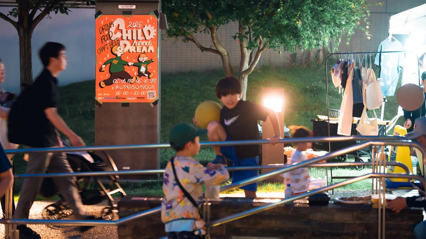 夜の会場で遊ぶ子どもたち。奥に「CHILDhood DREAM」のポスターと出店のテント