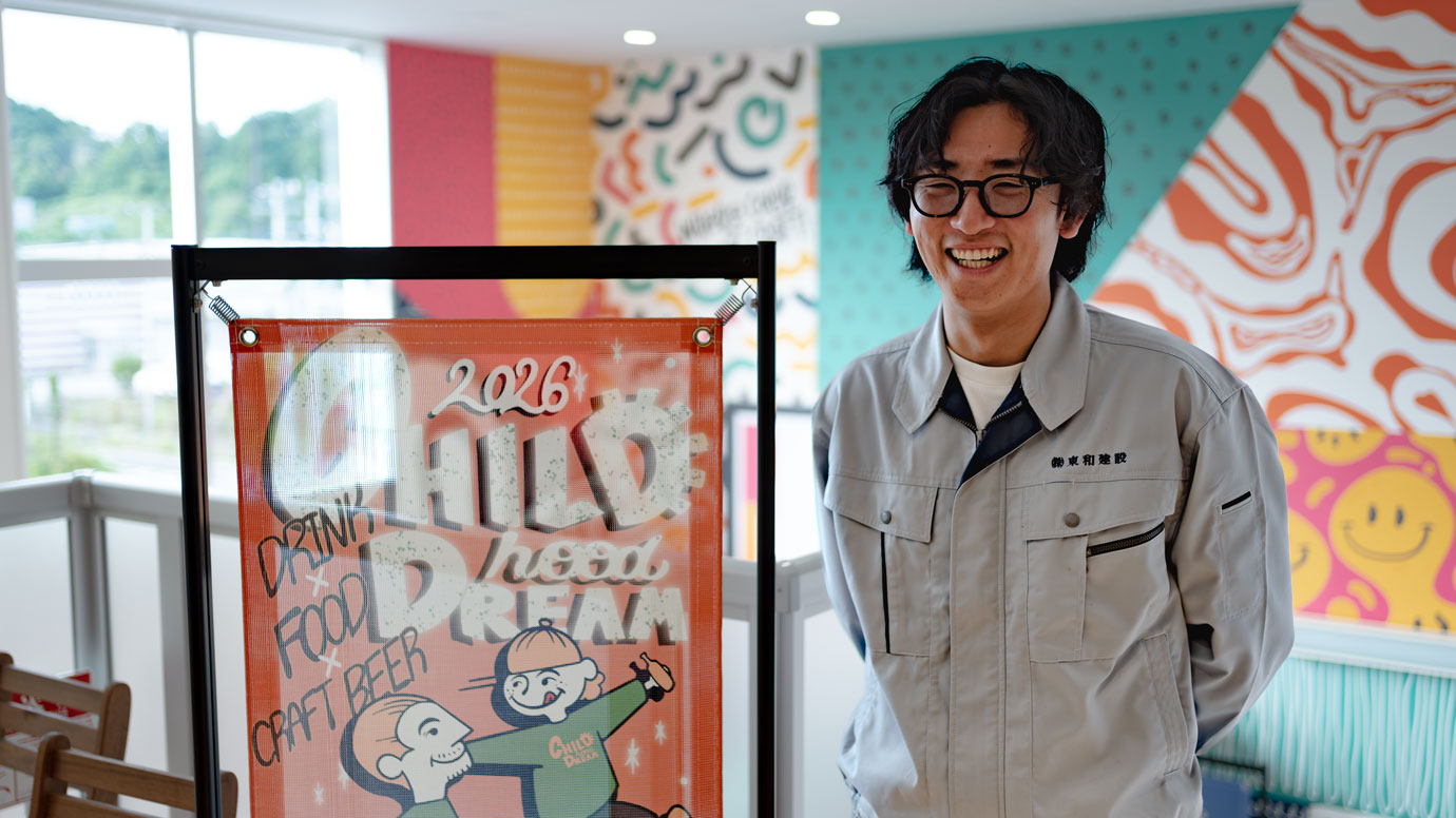 リニューアルしたサインアーテック正面エントランスの前に立つ松田陸氏と、イベントで使用したバナースタンド「どこでもバナー®」