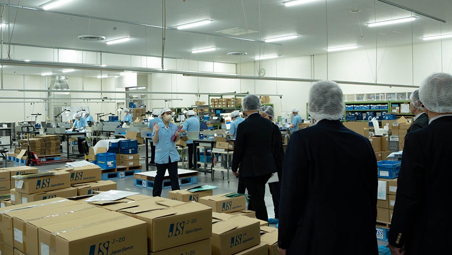 生産ラインを見学し、説明を受ける一同
